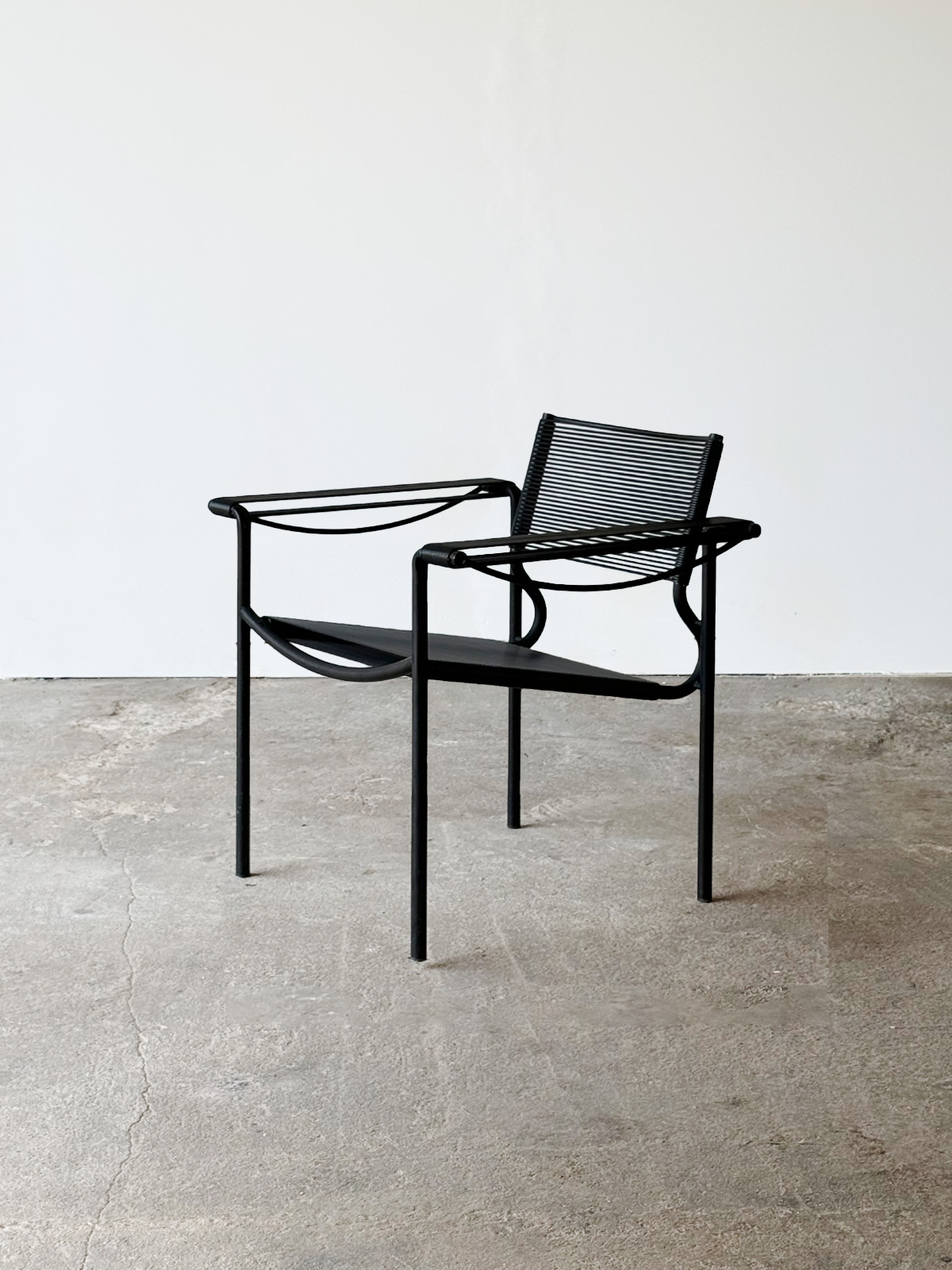 Fotel „Spaghetti” nr 109, widok od przodu, z czarną stalową ramą i siedziskiem wyplecionym z czarnej żyłki.