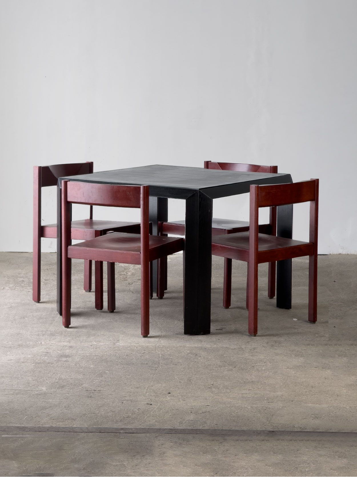 Cztery krzesła Santo w bordowym kolorze przy czarnym włoskim stole