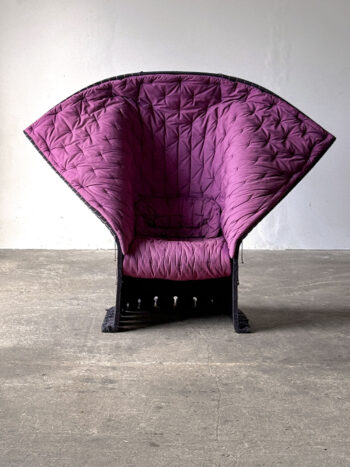 Fotel Feltri widziany od frontu, z fioletową tapicerką i szerokim siedziskiem
