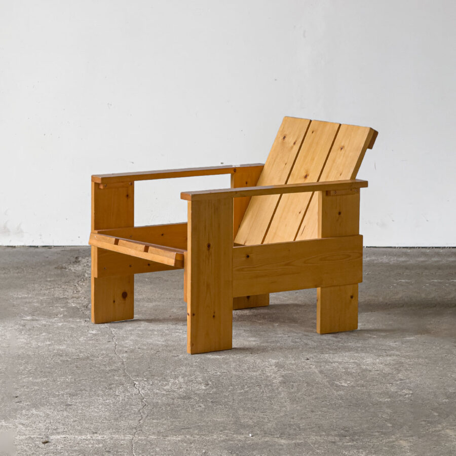 Fotel Crate z sosny w pełnym widoku, ustawiony na betonowej posadzce