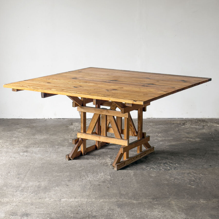 Kwadratowy stół z sosny według projektu Enzo Mari, widok z boku na tle szarej betonowej podłogi