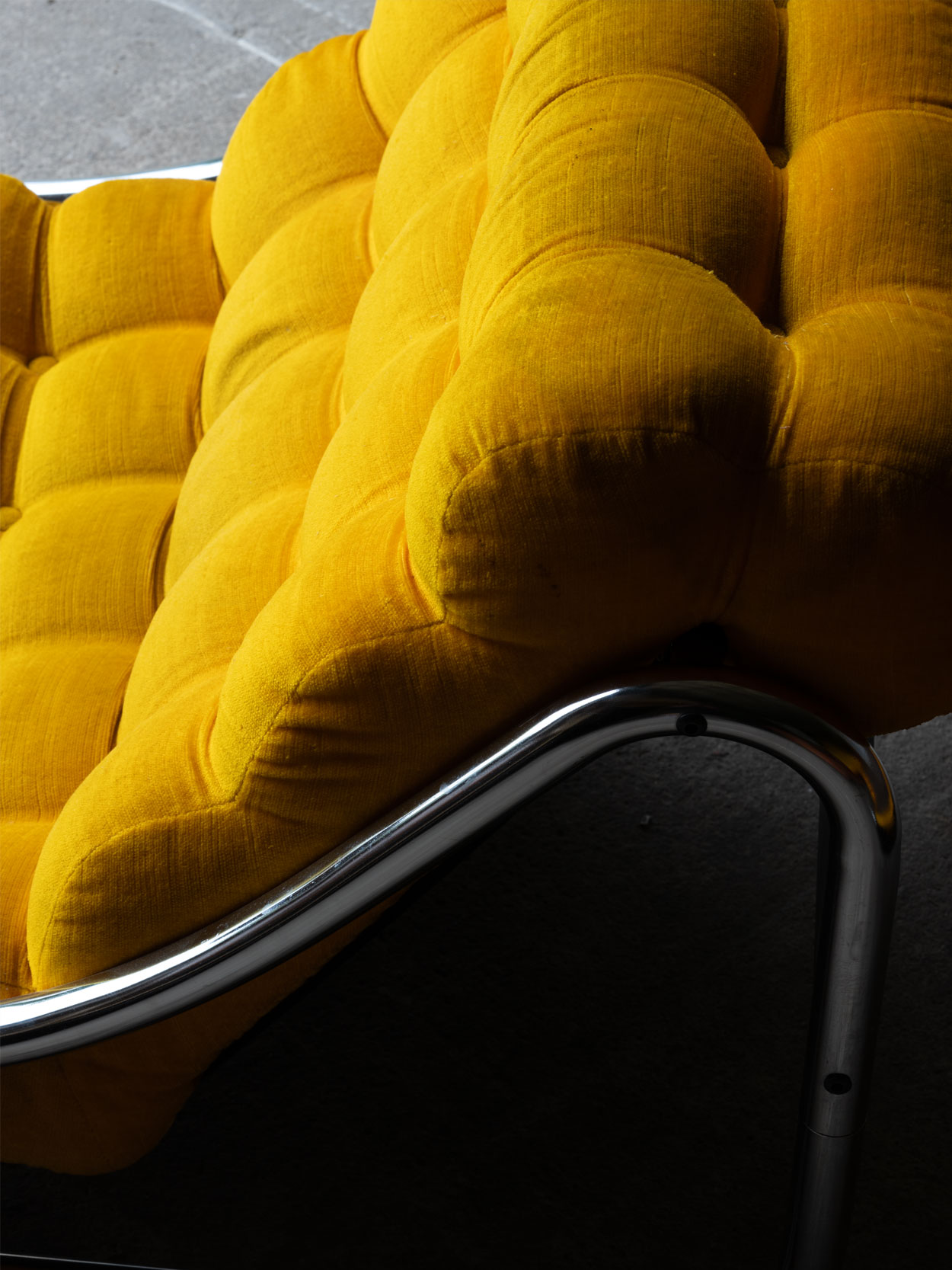Detal bocznej chromowanej ramy i żółtej tapicerki fotela Impala IKEA.